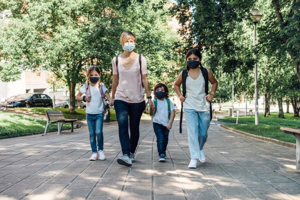 mom and children wearing masks while walking to school